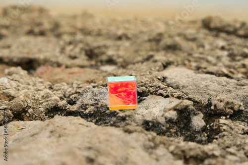 Geschliffenes, bunt schimmerndes Glas Quadrat auf einem Felsen am Strand, abstrakt und anders