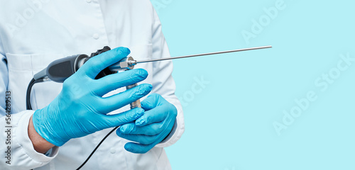 Video endoscope in hands of otolaryngologist for endoscopic check-up of ENT organs, isolated on blue background. Endoscopy photo