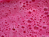 Magenta colorful bath foam with bubbles in the water.