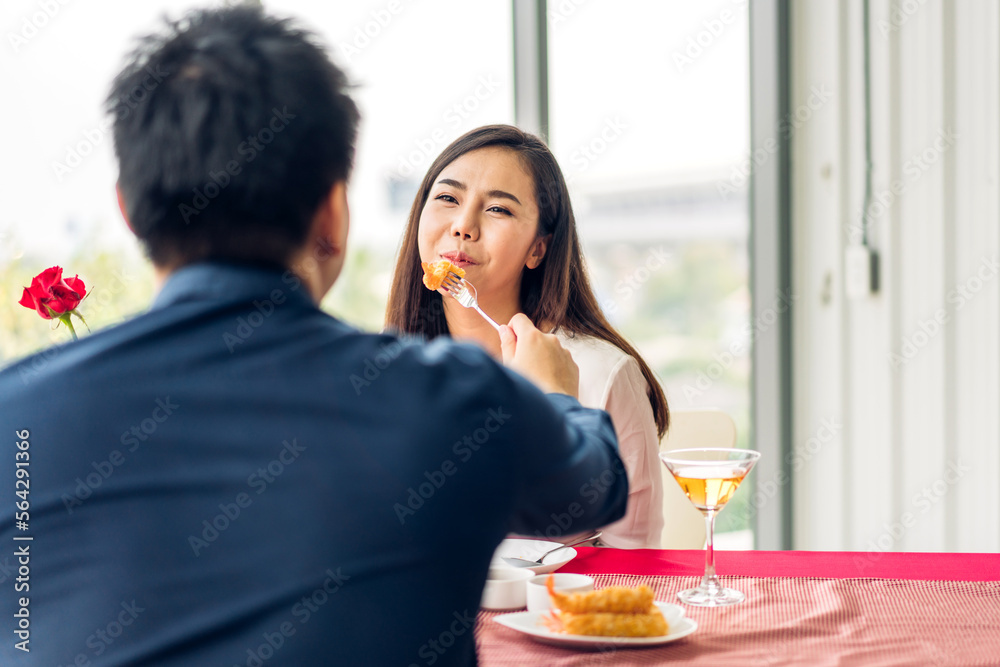 Romantic young asian happy love couple relaxing and talking together drinking wine glasses celebrating at dinner party lying on chair in the restaurant.date and anniversary concept