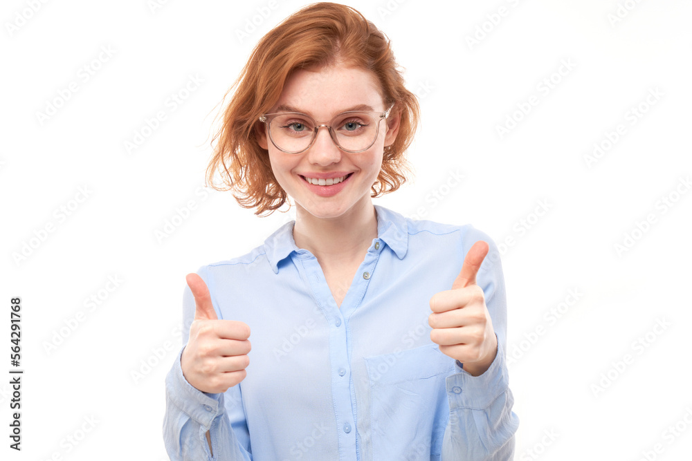 Young redhead woman shows hand with thumbs up and smiles at the camera isolated on white background Young redhead woman shows hand with thumbs up and smiles at the camera isolated on white background
