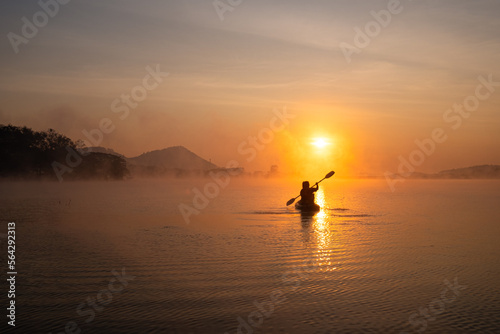 Fotografia Women on kayak rows in the reservoir during the sunrise, Harirak forest park Hua