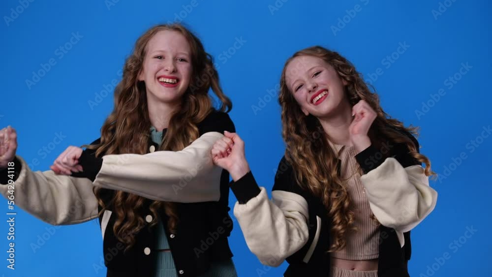 4k slow motion video of twin girls dancing over blue background. 4k slow motion video of twin girls dancing over blue background.