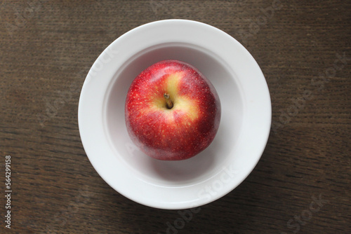 beautiful red apple in a white plate on a dark wooden surface