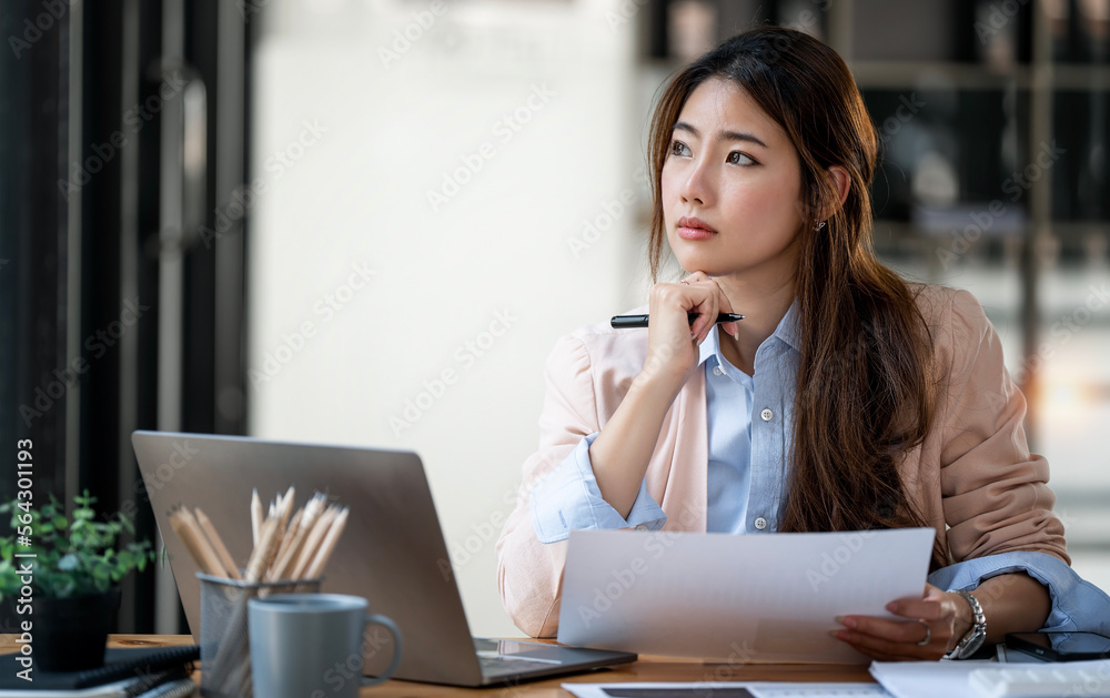 Serious young woman sitting at office, deep in thoughts, thinking concept Serious young woman sitting at office, deep in thoughts, thinking concept