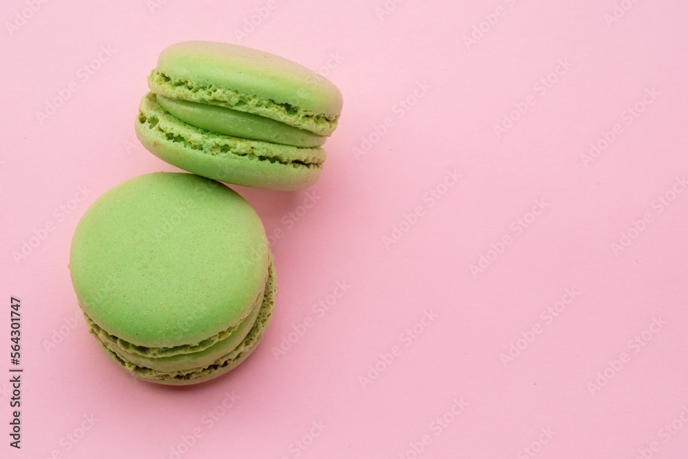 Two green french macarons isolated on pink background. Two green french macarons isolated on pink background.