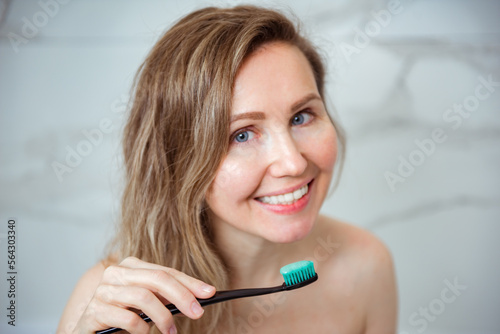Young beautiful woman is engaged in cleaning teeth. Beautiful smile healthy white teeth. A girl holds a toothbrush. The concept of oral hygiene