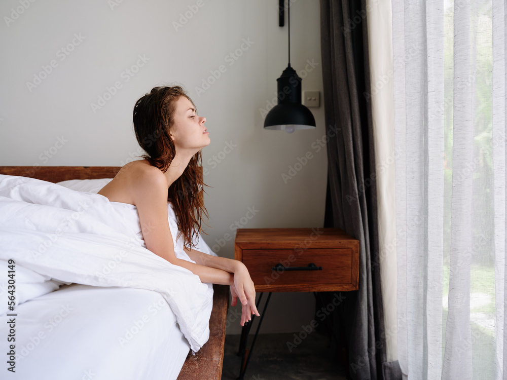 A woman after a shower lies on a bed in a bedroom near a window with wet hair, a healthy sleep on an orthopedic patras and a memory foam pillow, body and hair care A woman after a shower lies on a bed in a bedroom near a window with wet hair, a healthy sleep on an orthopedic patras and a memory foam pillow, body and hair care