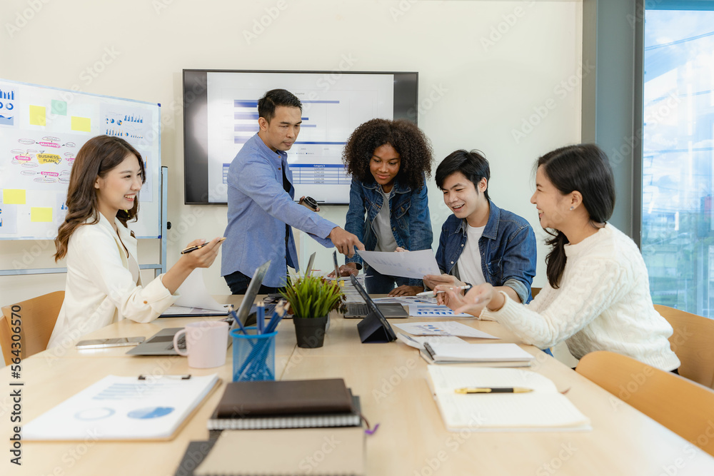 Group of Asian business people brainstorming at a meeting to start a new business. In a small office with a laptop and financial graphs on the table Group of Asian business people brainstorming at a meeting to start a new business. In a small office with a laptop and financial graphs on the table