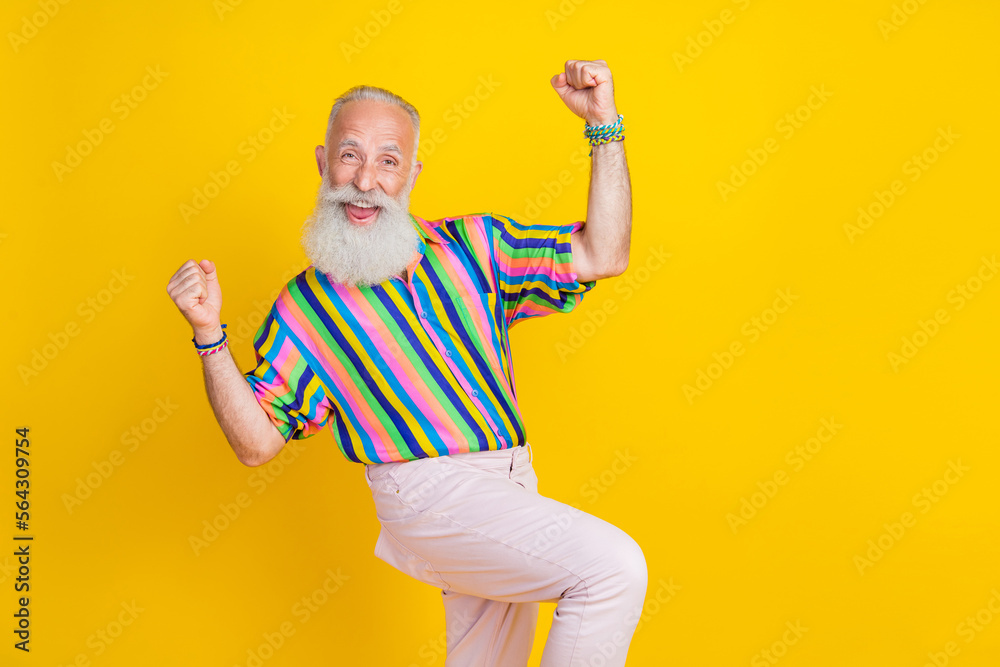 Photo of cool lucky guy dressed striped shirt shouting empty space rising fists isolated yellow color background Photo of cool lucky guy dressed striped shirt shouting empty space rising fists isolated yellow color background