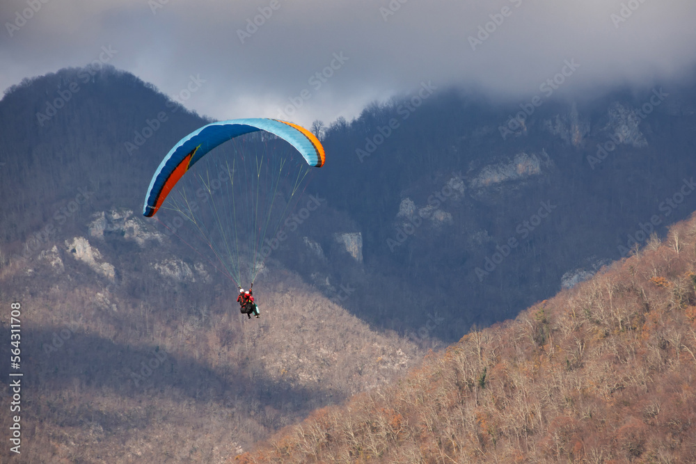 Paraglider flies against the backdrop of mountains and a forest of clouds. Paraglider flies against the backdrop of mountains and a forest of clouds.