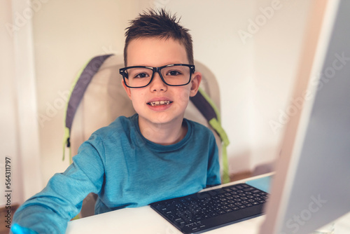 Boy doing homework in his room, seating on the chair and work on the desk.