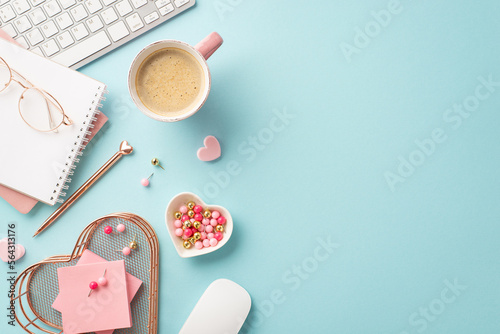 Top view photo of keyboard notepads pen heart shaped stationery holder pushpins sticky note paper glasses computer mouse and mug of coffee on isolated pastel blue background with copyspace