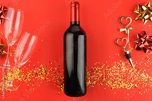 Still life with a bottle of wine, a corkscrew and a cork with heart-shaped handle on red background. View from above.