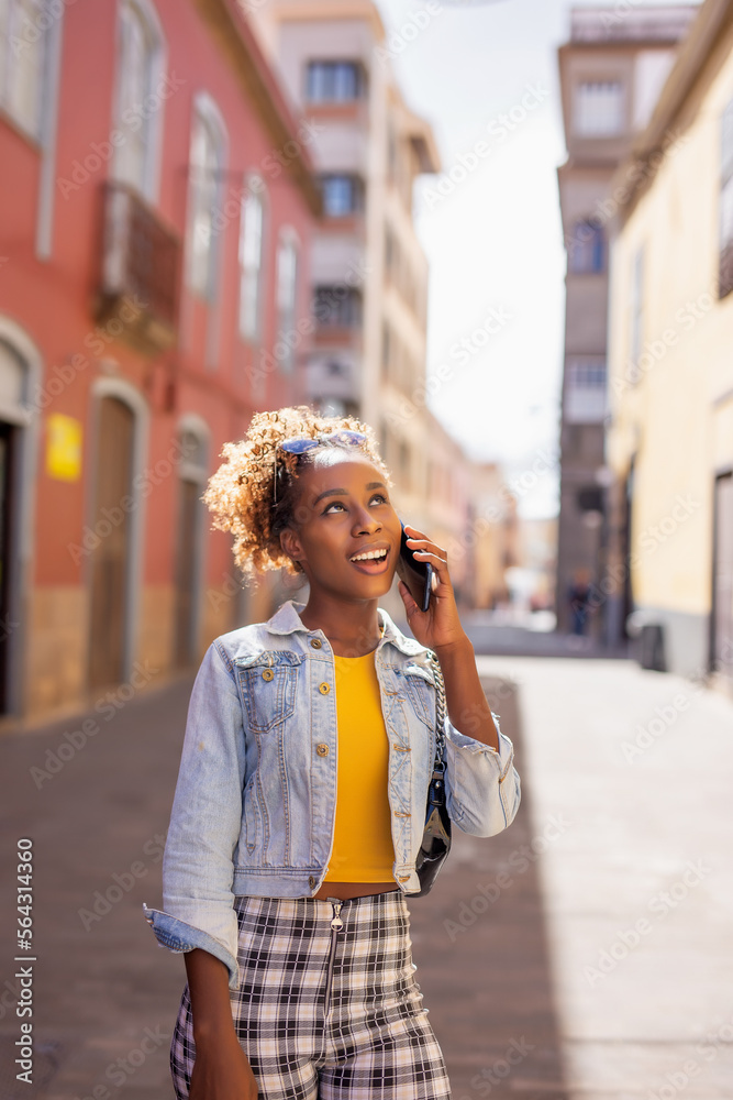 Fototapeta premium Happy woman walking using a cellphone in the street
