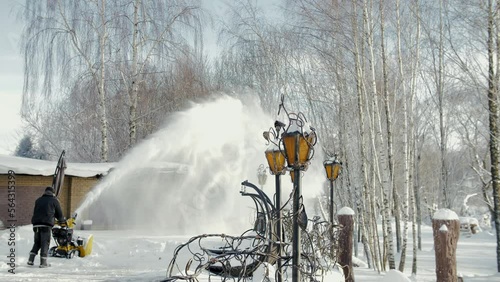  Slow motion video of the snow that flies against the backdrop of the setting sun before sunset. Close-up on snow in winter from a snowplow 