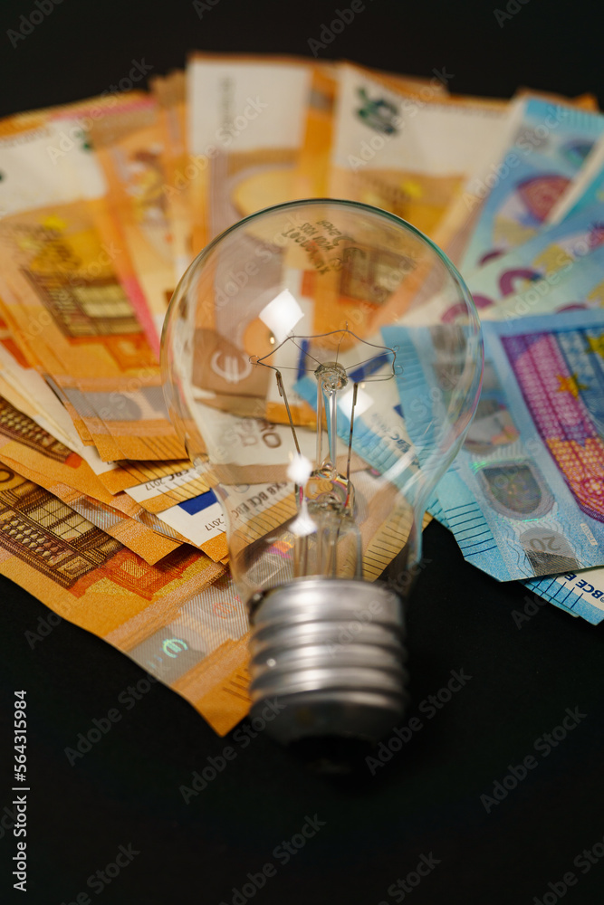 lighted light bulb with euro banknotes in the background lighted light bulb with euro banknotes in the background