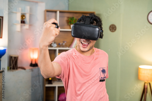 sweet excited young man with VR or virtual reality goggles doing workout by using joystick at home - concept of metaverse  health care and technology.