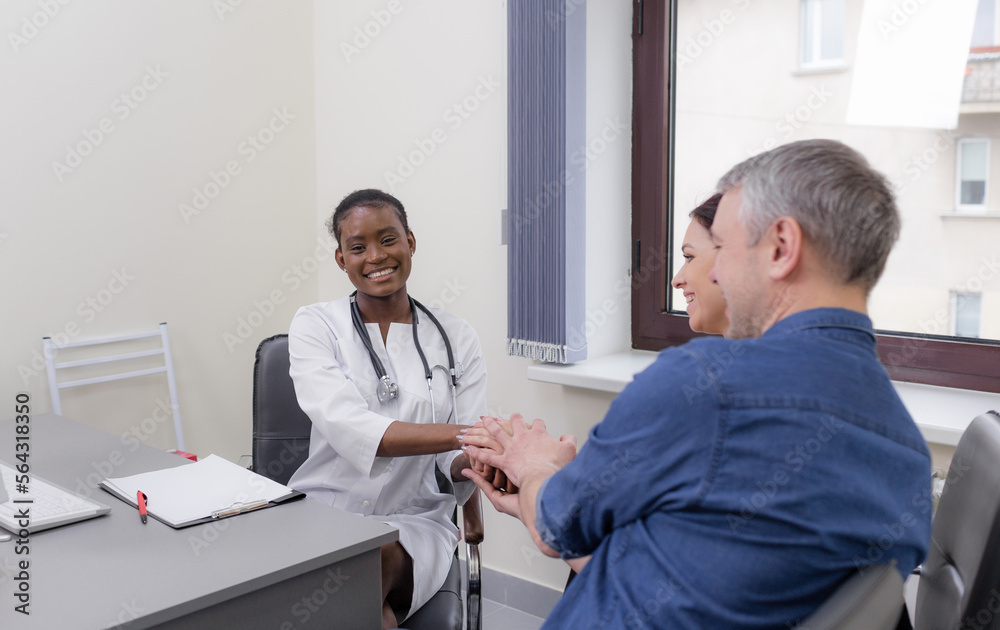a happy married couple thanks the doctor by shaking his hand. Consultation with a family doctor, positive health news a happy married couple thanks the doctor by shaking his hand. Consultation with a family doctor, positive health news