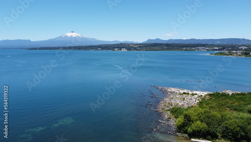 Aerial view of the volcano and mountains, on the shore of a lake in summer, with the city in the distance.