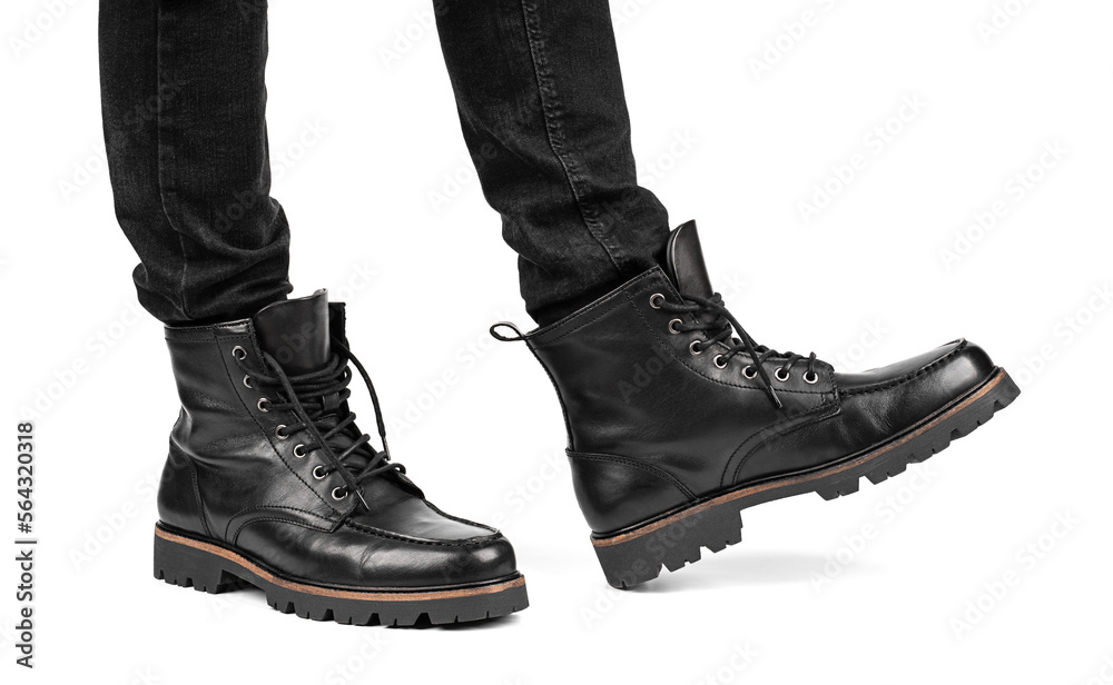 Pair of black leather boots, dress boots for men, men ankle high boots. Black brogue boots on a white background. Men fashion in leather boots. Man's legs in black jeans and brown leather boots.