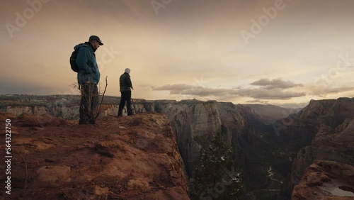 Hikers standing at the edge of Zion Canyon at sunset / Springdale, Utah, United States photo