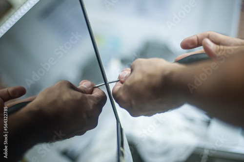 Maintenance, professional service cleaning. A repairman opens a computer monitor with a screwdriver. Close-up of specialized manual cleaning of laptop.