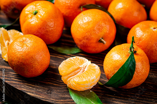 Juicy tangerines with leaves on a wooden tray. 