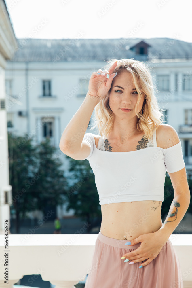 a blonde woman stands on a balcony with her hands to her face a blonde woman stands on a balcony with her hands to her face
