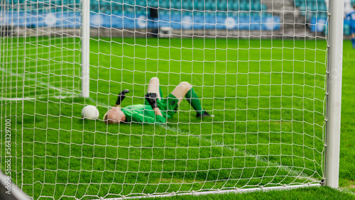 Soccer Football Championship Match: Goalkeeper Loses the Ball in a Goal and Lays on the Grass. Live Sport Channel Broadcast Television Concept. Stylish, Through Goals Net Shot. © Gorodenkoff