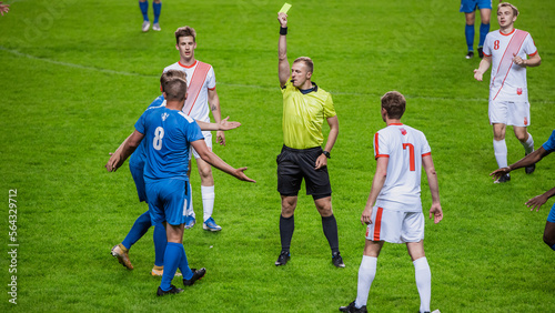 Soccer Football Championship Match  Referee Sees Foul  Gives Signal and Yellow Card  Players Circle him Upset. International Tournament. Sport Broadcast Channel Television Concept.