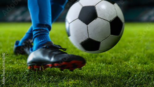Close-up of a Leg in a Boot Kicking Football Ball. Professional Soccer Player Hits Ball with Fierce Power and Scores Goal, Grass Flying. Beautiful Cinematic Low Angle Ground Artistic Shot © Gorodenkoff