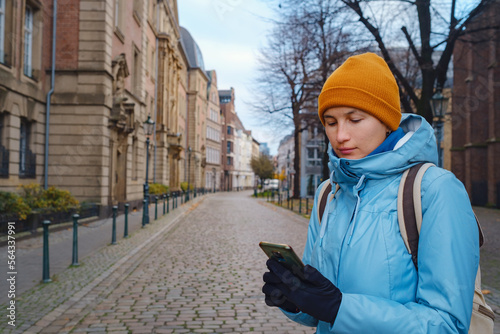 winter travel to Dusseldorf  Germany. young Asian tourist in blue jacket and yellow hat  symbol of Ukraine  look map  got lost in old town or Altstadt. Popular center of Rheinland and Westphalia