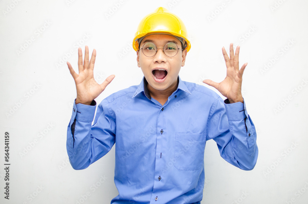 asian construction worker wearing yellow safety helmet shouting with shocked and surprised expression.