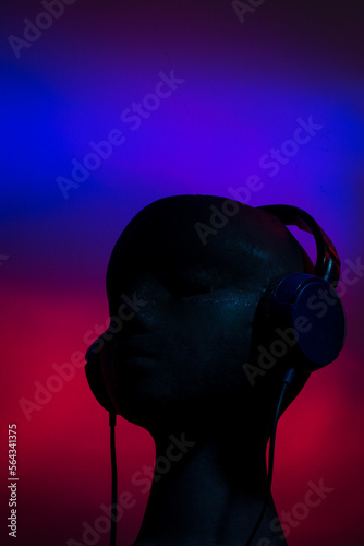 Over-ear headphones on black head on blue and red background