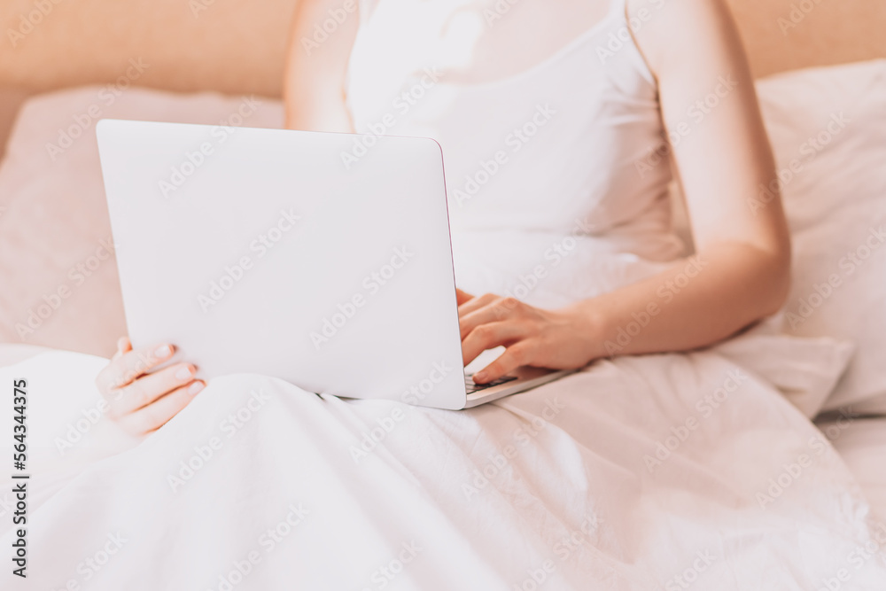 Lady working on a laptop in bed with white linens. Lady working on a laptop in bed with white linens.