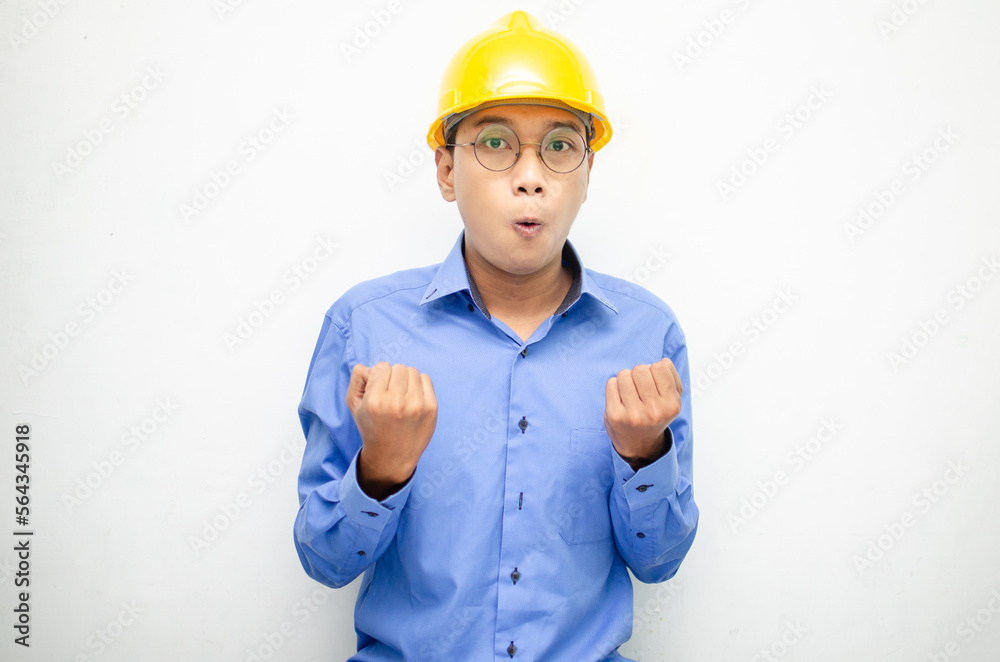 asian construction worker wearing yellow safety helmet shouting with shocked and surprised expression.