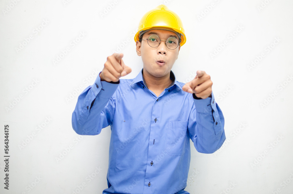 asian construction worker wearing yellow safety helmet and smiling and pointing finger with happy and shocked expression. billboard model advertisment concept. construction worker presenting something
