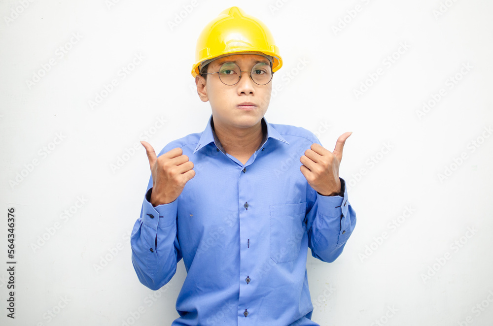 Young Asian man construction worker in yellow safety helmet unsure of what to choose with hand pointing left or right, isolated over whote background. advertising model for billboards.