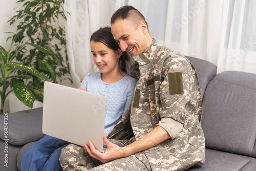 Happy girl sitting with military man near laptop.