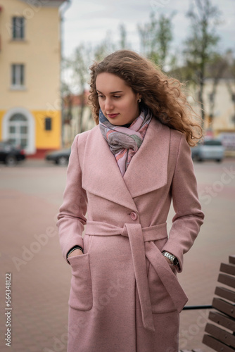 Portrait of a young beautiful long-haired girl in a gray coat in a spring park.