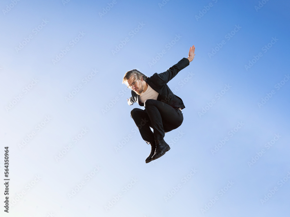 businessman jumping doing parkour with long blonde hair and glasses executive business clothes