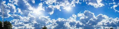 Bright blue skies and fluffy white clouds on a bright and sunny day - A panoramic view of the sky made by generative AI