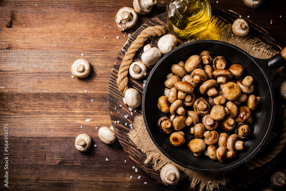 Frying pan with fried mushrooms on a wooden tray. Frying pan with fried mushrooms on a wooden tray.