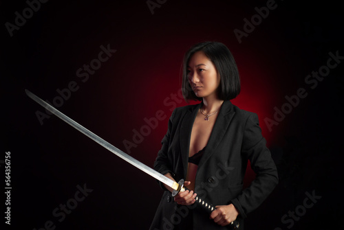 portrait of an Asian girl with a katana in her hands posing emotionally on a black background copy paste