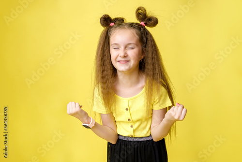 Cool cute girl with a trendy hairstyle in a yellow top on a yellow background with bright emotions