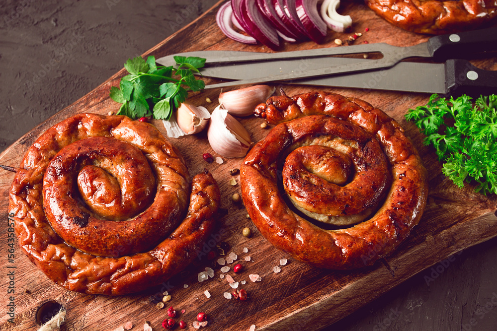 Fototapeta premium Fried spiral sausages, on a wooden board, top view, with spices, no people