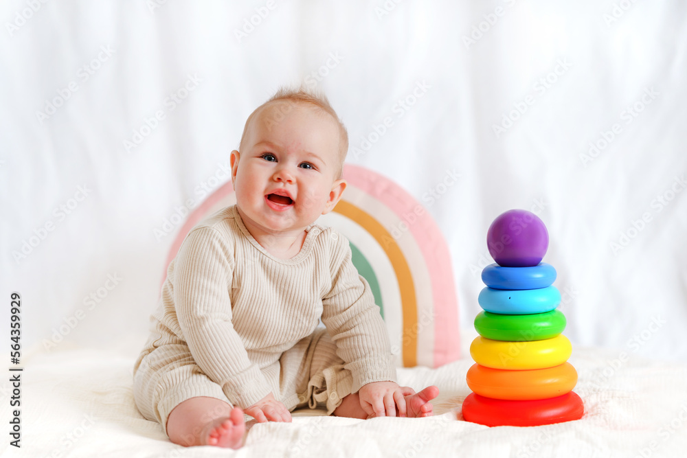 A little baby toddler is sitting next to toys on a white background A little baby toddler is sitting next to toys on a white background