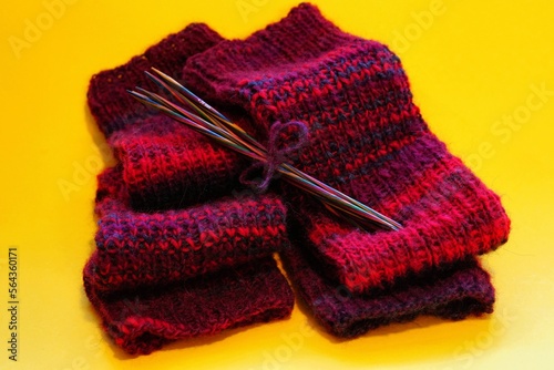 rote stulpen mit holz stricknadeln, trend stricken, gelber hintergrund