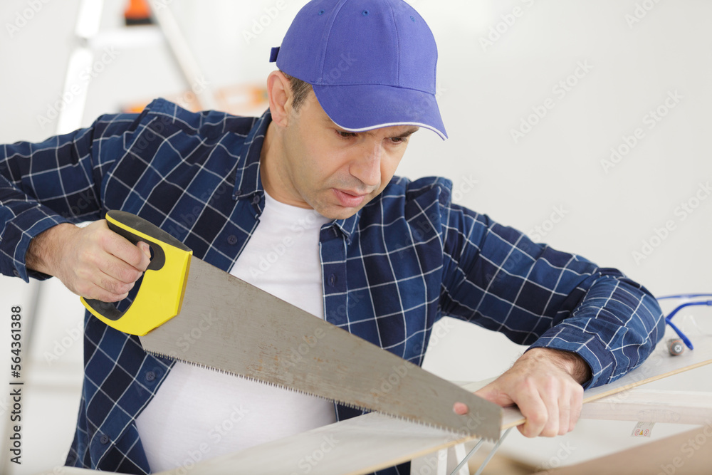senior carpenter using a handsaw